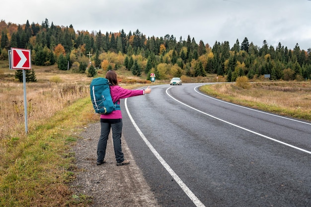 Viajes turista mujer mochilero haciendo autostop en viaje por carretera haciendo autostop en coche