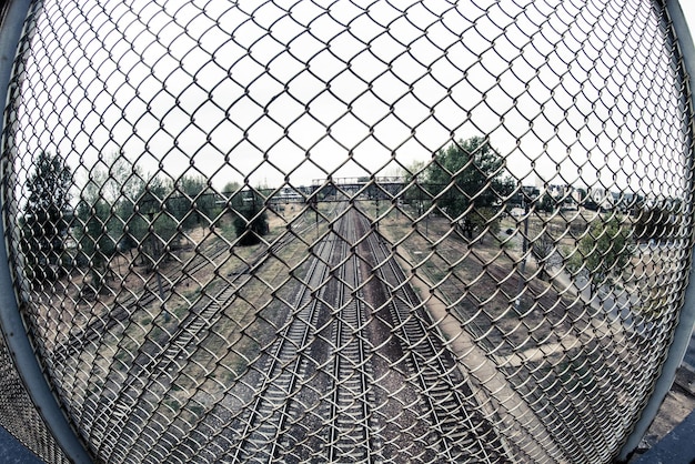 Foto las vías del ferrocarril contra el cielo despejado vistas a través de la valla de cadena