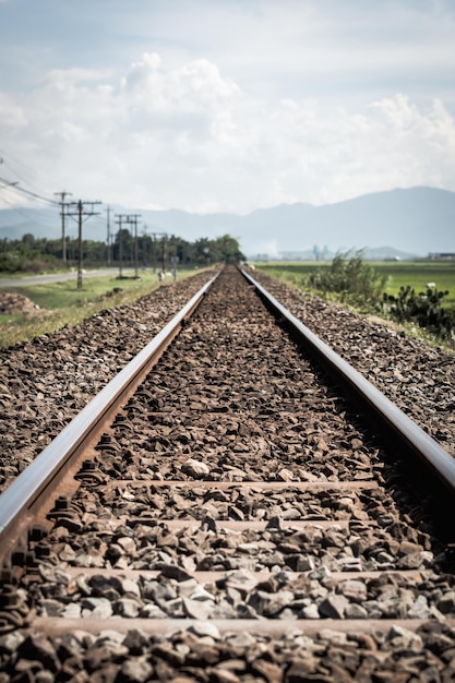 Vías ferroviarias línea adelante grava horizonte belleza nublado cielo azul postes eléctricos paisaje sol montaña fondo Ferrocarril viajes turismo transporte industrial concepto mañana de verano