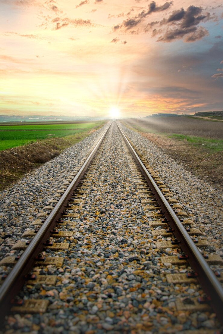 Foto vías de tren convergentes hacia el sol.