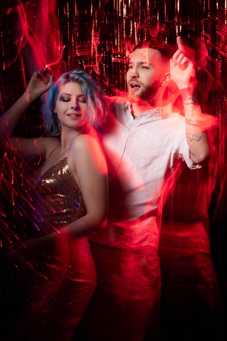 Foto vibração de festa casal dançante alegria de natal celebração festiva feliz homem e mulher expressivos aproveitando o feriado de longa exposição luz de néon vermelho preto ondas de movimento borrão