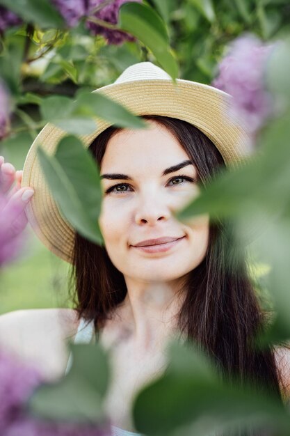 Vibraciones florales de verano Una mujer con un sombrero de paja posando en flores en flor en el parque Retrato de verano de una joven latina