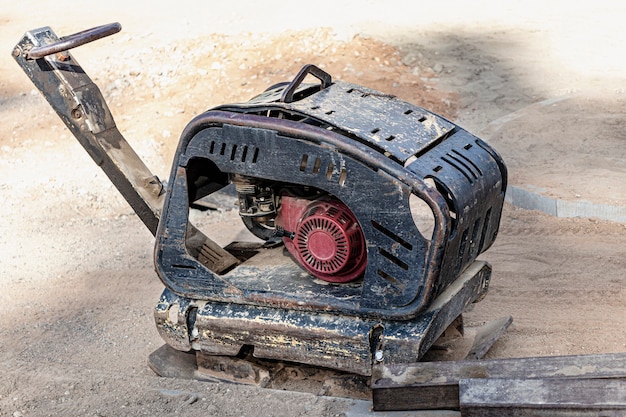 Vibrationsstampfer mit Vibrationsplatte auf einer Baustelle. Verdichtung des Bodens vor dem Verlegen von Pflastersteinen. Nahaufnahme.