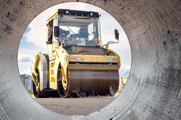 Vibrationsstraßenwalze legt Asphalt auf einer im Bau befindlichen neuen Straße Nahaufnahme der Arbeit von Straßenbaugeräten Moderne Arbeiten zum Bau von Straßen in der Stadt Blick von der großen Pfeife