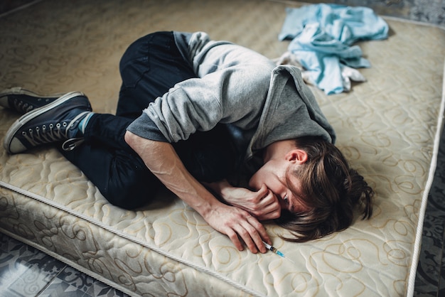 Viciado em drogas dormindo na cama após a dose