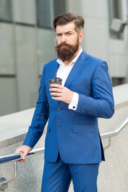 Viciado em estilo. homem formal em terno de escritório bebendo café do copo de papel. bom dia café. levar bebida. empresário confiante precisa de inspiração. empresário barbudo bebe café para viagem.