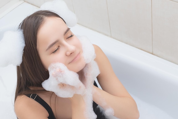 Vida divertida y feliz Mujer joven en el baño está jugando con espuma