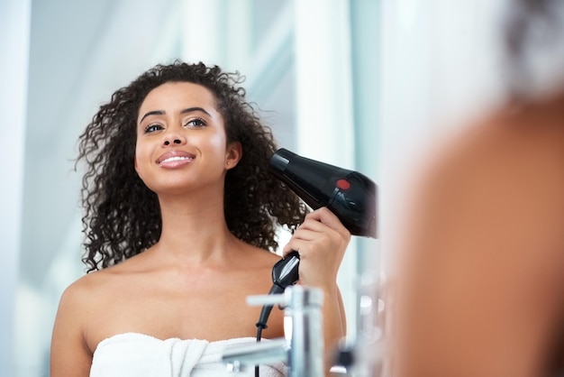 La vida es demasiado corta para tener un cabello aburrido Foto de una atractiva joven secándose el cabello en casa