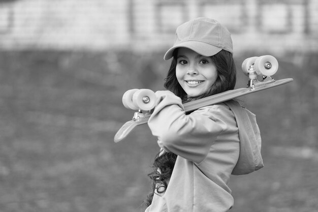 La vida es mucho con el monopatín Niña feliz sostiene un tablero de penny al aire libre Patineta callejera Deporte y ocio Transporte y transporte Vacaciones de otoño Estilo de vida activo Vivir y andar en patineta