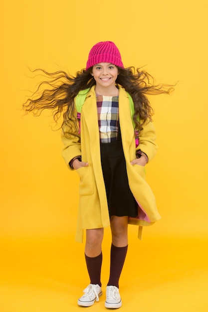 Foto vida escolar colegiala elegante niña pequeña alumna de moda usar sombrero de punto y chaqueta traje moderno traje de invierno de colegiala adorable traje diario de colegiala con mochila accesorio de moda