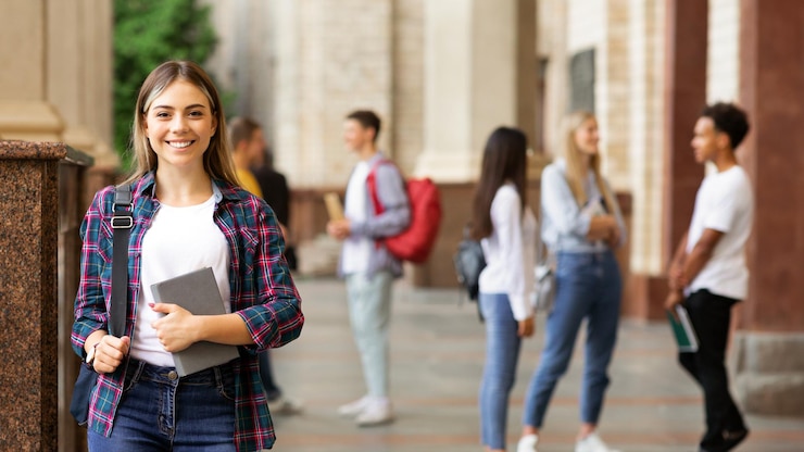 Foto vida estudiantil niña feliz con libros y sonriendo al aire libre