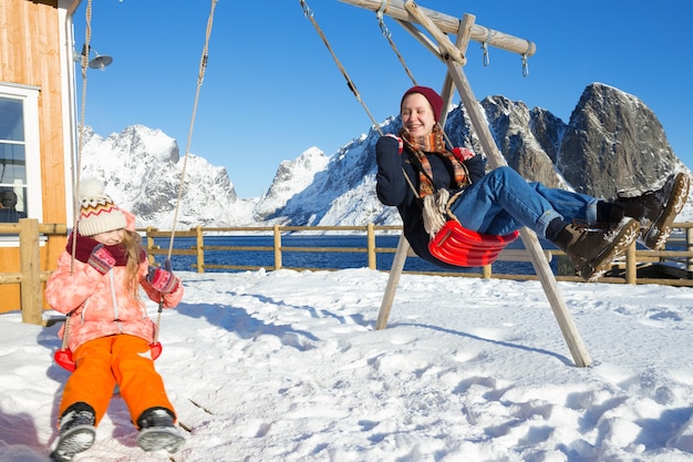 Vida feliz y divertida. Hermana de niñas columpiándose en un columpio en las islas Lofoten. Noruega