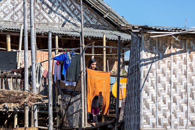 La vida en el lago Inle La niña cuelga la ropa lavada cerca de la casaMyanmar