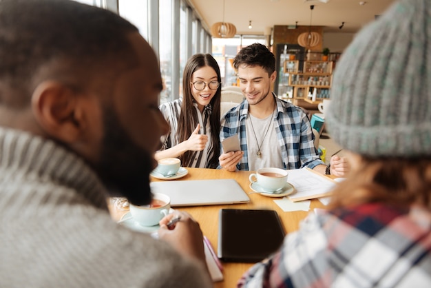 Vida moderna. cara legal está compartilhando informações em seu smartphone com sua linda namorada durante uma reunião no café.