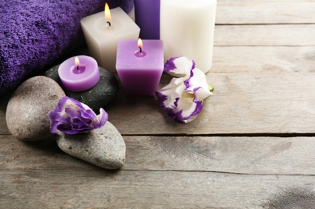 Vida morta de spa com flores roxas toalhas velas e seixos em fundo de madeira