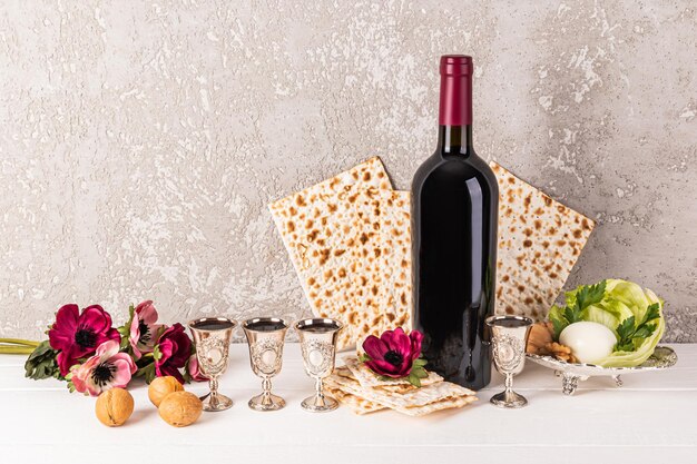 Vida muerta festiva para la fiesta judía de primavera de la Pascua Comida tradicional kosher una botella de vino rojo y vasos de plata con vino derramado.