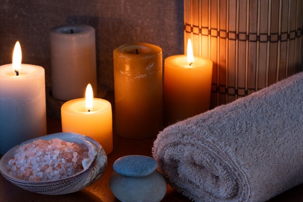 Vida muerta de spa con velas, toalla y sal marina en una mesa de madera.