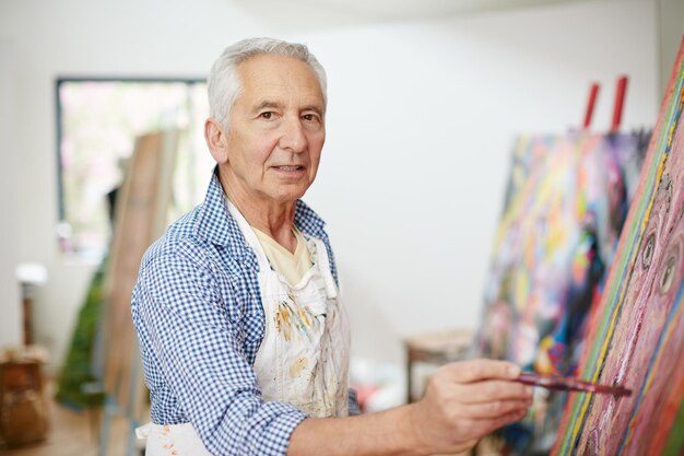 La vida no se trata de encontrarte a ti mismo, sino de crearte a ti mismo Foto de un hombre mayor trabajando en una pintura en casa