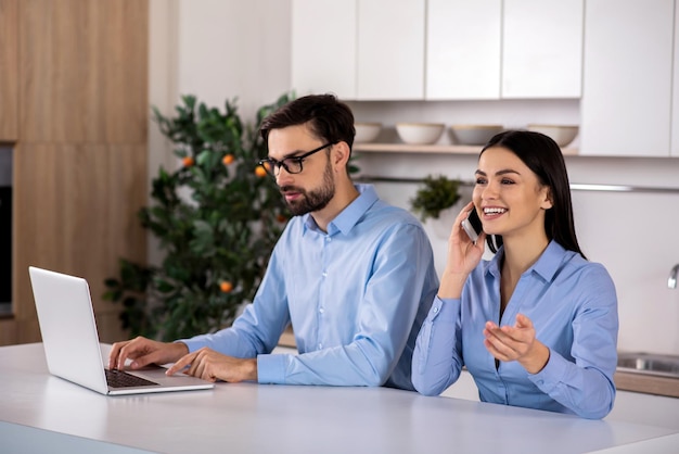 Vida positiva Empresária alegre falando ao telefone enquanto seu colega usa laptop