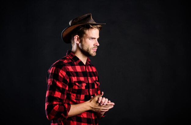 La vida del vaquero llegó a ser muy romantizada. Concepto de masculinidad y brutalidad. Adopta gestos de vaquero como pose de moda. Hombre vaquero sin afeitar fondo negro. Imagen arquetípica de los estadounidenses en el extranjero.