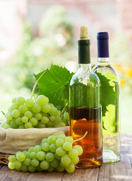 Videira de garrafas de vinho branco e cacho de uvas ao ar livre