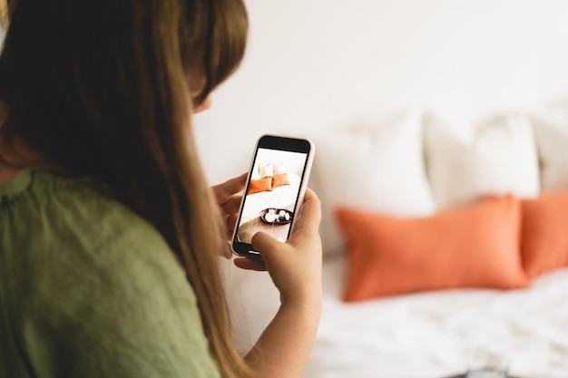 Video blog Una mujer joven está filmando artículos para el hogar para su tienda en línea con la cámara de su teléfono. Ejecutando un video blog. Un vlogger transmite en línea usando un teléfono. Redes sociales quédese en casa y en cuarentena.