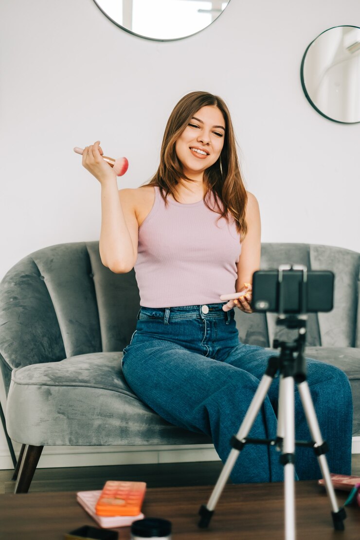 Foto vídeo-blogueira jovem e atraente mostrando produtos de beleza por meio de seu blog nas redes sociais