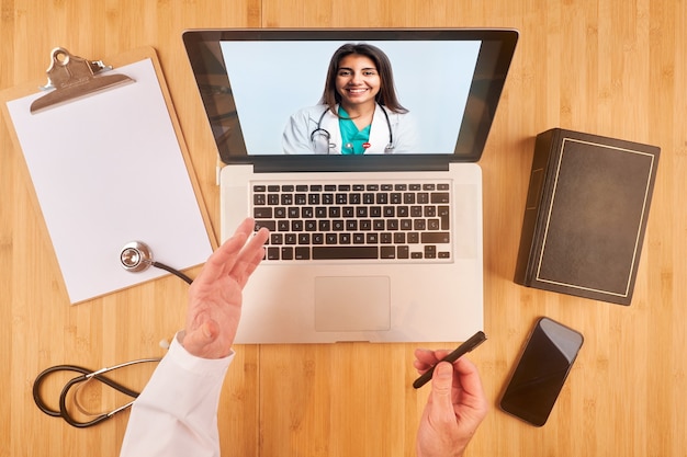 Foto video chat online de un joven médico latino con un colega