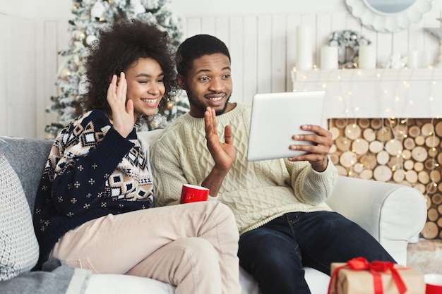 Vídeo de saudação de natal. casal afro-americano batendo papo online, parabenizando família ou amigos com tablet digital, copie espaço