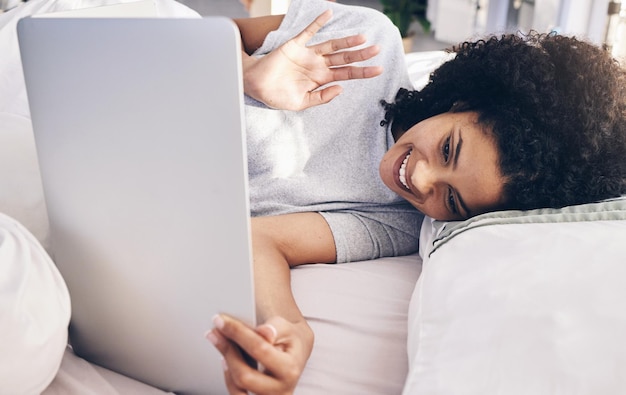 Videoanruf Laptop und Frau winken im Bett im Schlafzimmer für Online-Chat am Morgen Technologiekommunikation und schwarze Frau winkt auf virtueller Konferenz, während sie mit dem Computer spricht