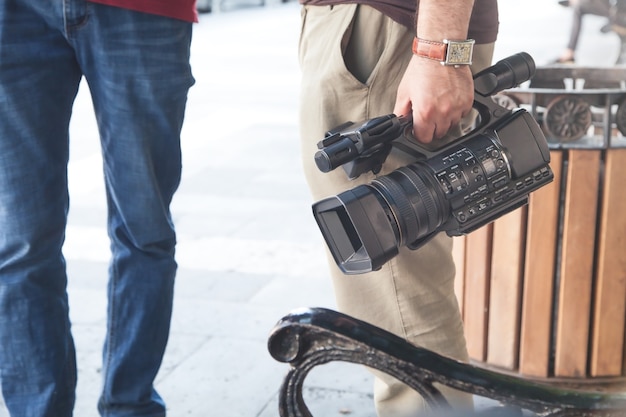 Videobetreiber, der professionelle videokamera in einer stadt hält.