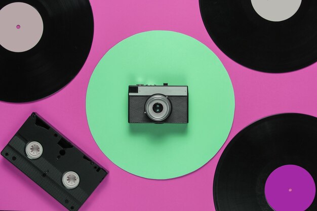 Videocassete de vinil retro, câmera de filme em um fundo de cor rosa com um círculo verde. vista do topo