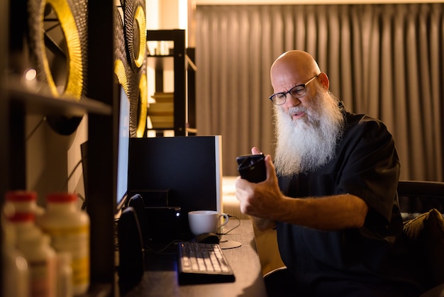 Videochamada de homem maduro de barba careca estressado enquanto trabalhava horas extras em casa tarde da noite