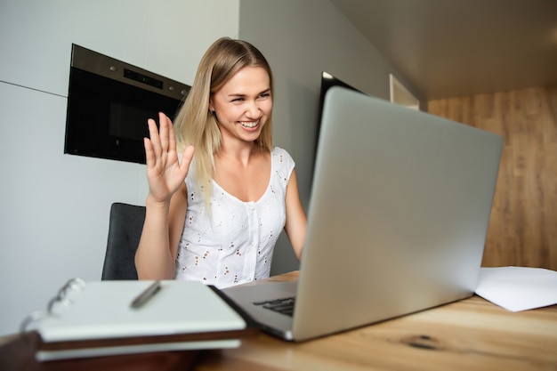 Videochamada, videoconferência com outras pessoas no laptop dentro de casa. Aprendizagem e trabalho online. Mulher com laptop trabalhando em casa