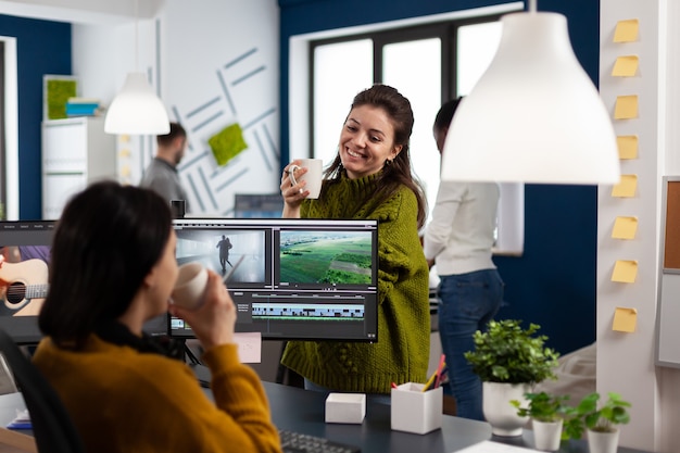 Videofilmer trinken Kaffee und reden während der Arbeitspause am Schreibtisch im Büro der Kreativagentur