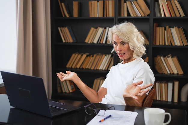 Foto videogespräch glückliche ältere frau mittleren alters sitzt mit laptop und spricht über video-gespräch reife alte ältere dame