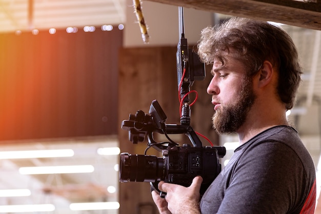 Foto videógrafo gravando um filme ou programa de televisão em um estúdio com uma câmera profissional, nos bastidores