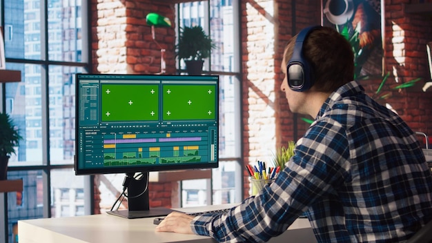 Videógrafo haciendo montaje de video usando software especializado en una PC de pantalla verde