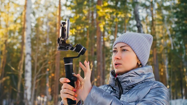 Videógrafo profesional con cámara DSLR en dispositivo de estabilización de cardán de 3 ejes en cámara lenta de operador de cineasta de invierno