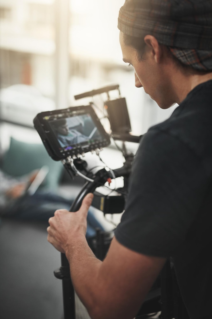 Foto videokamera und mann, die im studio für fotografie, produktion und medien dreht hinter den kulissen und person mit stabilisierungsgeräten auf dem set, die videos, dokumentarfilme und filme dreht