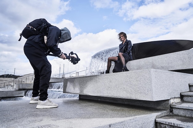 Videokameramann, der mit Mode-Modellmädchen im Freien arbeitet