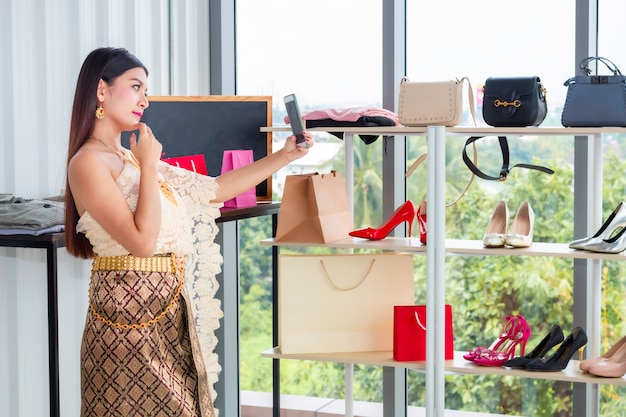 Foto videollamada hermosa de la mujer con el teléfono en el traje tradicional nacional de tailandia en la tienda shpping.