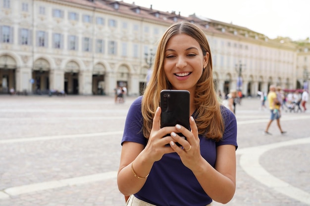 Videollamadas de chica milenaria con smartphone contra fondo urbano