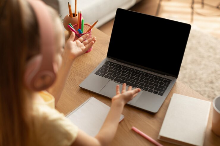 Foto videollamadas de niña a través de una computadora portátil con pantalla vacía en el interior