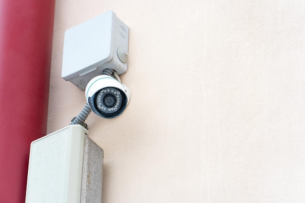 Videoüberwachungssysteme Sicherheitssysteme und Schutz vor Diebstahl CCTV-Sicherheitskamera an der Fassade eines Wohngebäudes Digitaltechnik orangefarbener Hintergrund