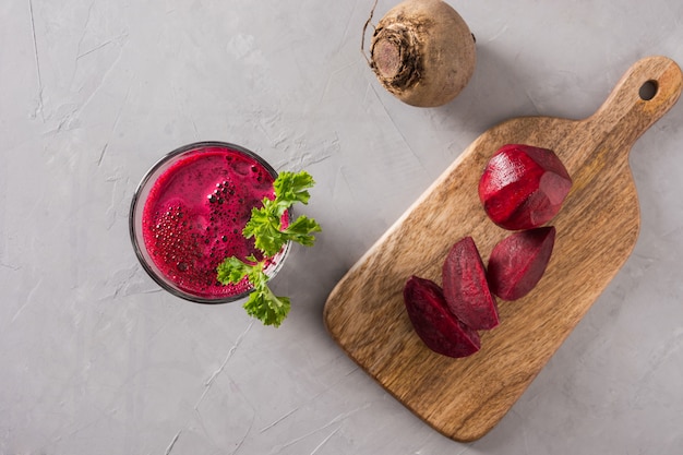 El vidrio de jugo fresco de las remolachas adorna el perejil en gris.