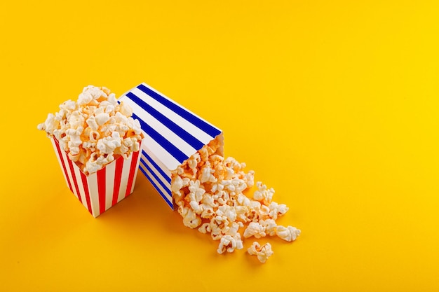 Vidrio con palomitas de maíz sobre un fondo amarillo