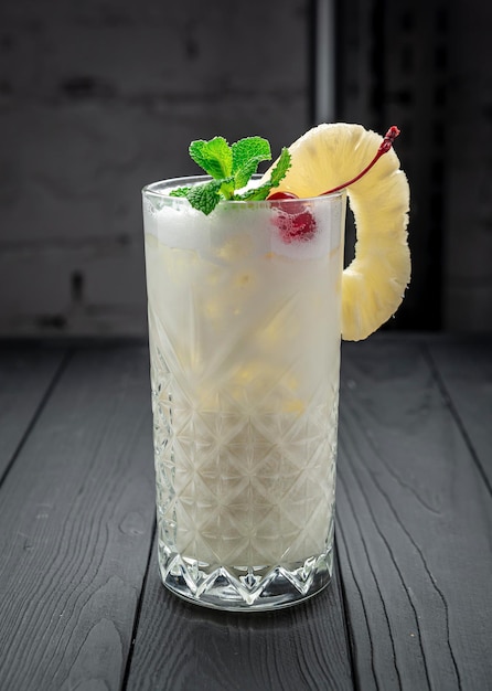 Vidrio con piña colada sobre fondo oscuro