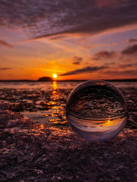 Foto vidrio en la playa contra el cielo durante la puesta de sol