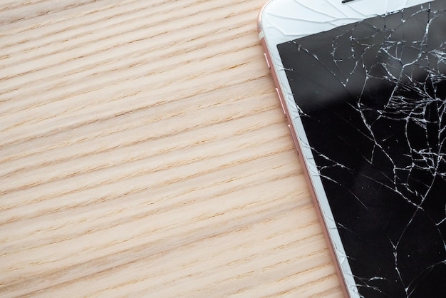 Vidrio roto de la pantalla del teléfono móvil sobre fondo de madera